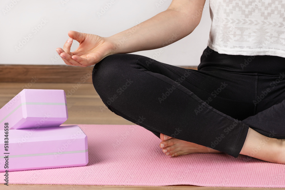 Obraz premium Yoga woman sitting in lotus asana and breathing. Yoga workout with yoga blocks.