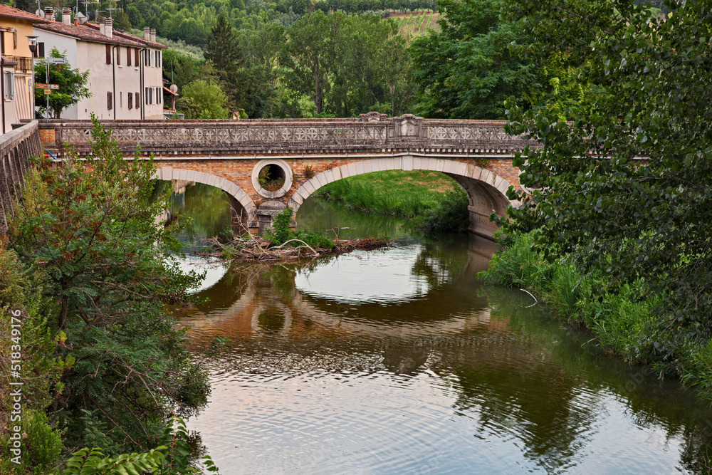 Fiumana, Predappio, Emilia Romagna, Italy - landscape of the village with the river Rabbi and the ancient bridge built in the 20-30s in rationalist architecture Fiumana, Predappio, Emilia Romagna, Italy - landscape of the village with the river Rabbi and the ancient bridge built in the 20-30s in rationalist architecture