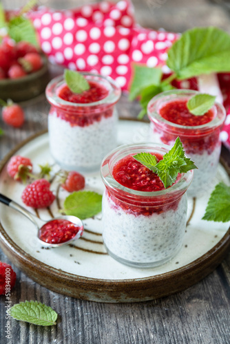 Healthy breakfast. Glass jars with chia pudding with raspberry and jam or smoothies with chia seeds on rustic table. Copy space.