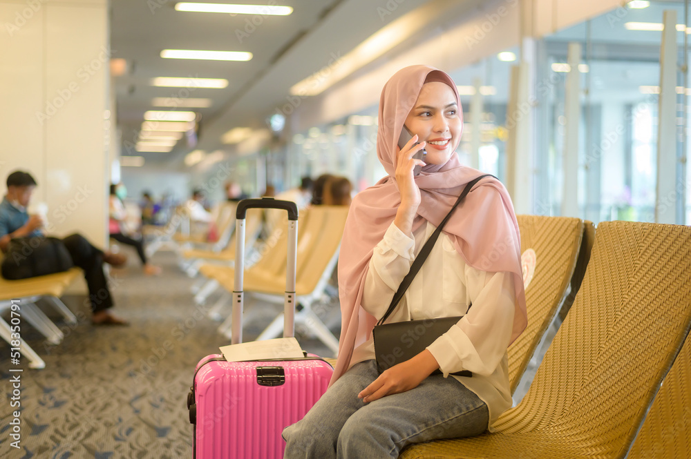 Fototapeta premium Young female muslim traveler carrying suitcases at the International airport, travel, holidays and journey concept..