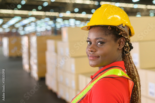 Portrait of young mixed race female worker wearing helmet in modern warehouse storage of retail shop photo