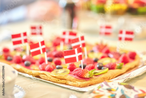 Danish fruit pastry for dessert to celebrate patriotism on Constitution Day in June. Annual holiday feast in Denmark with national flags in food. Fresh summer produce on a baked puff pastry