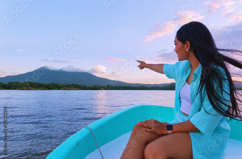Woman enjoying boat ride at isletas de Granada and pointing towards the Mombacho volcano photo