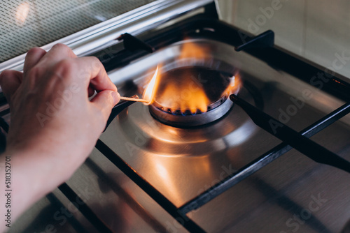 Obraz na płótnie A woman's hand with matchstick lights gas stove in her apartment w salonie