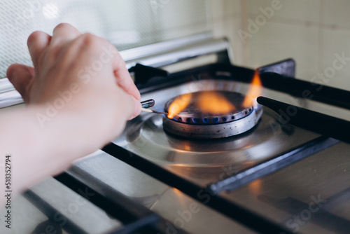 A woman's hand with matchstick lights gas stove in her apartment