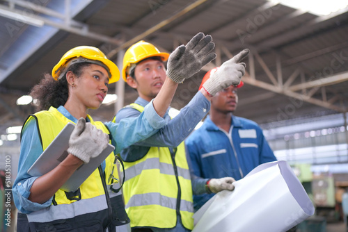 Three Heavy Industry Engineers Stand in Pipe Manufacturing Factory, Use Digital Tablet Computer, Have Discussion. Design and Construction