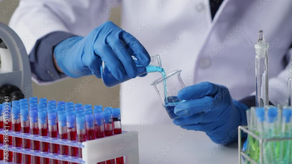 Close up of scientist’s hands using tube test and beaker for measuring the chemicals solution and observation on simple test in laboratory table that full of test tubes and beakers. Close up of scientist’s hands using tube test and beaker for measuring the chemicals solution and observation on simple test in laboratory table that full of test tubes and beakers.