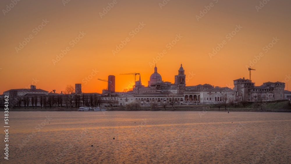 View of Mantua historic center from the upper lake. Sunset February 2022, visible the basilica, the Gonzaga castle and the bridge that connects the city on the north side. You can see the many medieva