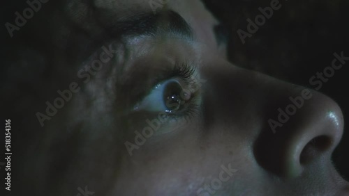 focus on the staring eye of young psychotic woman under a flashing light