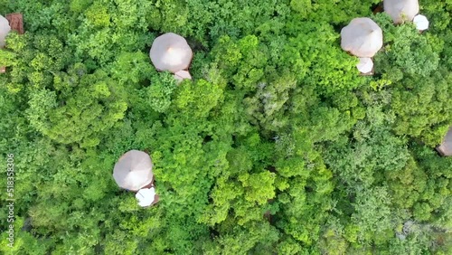 Aerial panoramic view flying over some natural bungalows, tree houses and a tropical beach surrounded by a green forest in Baru, Cartagena, Colombia
