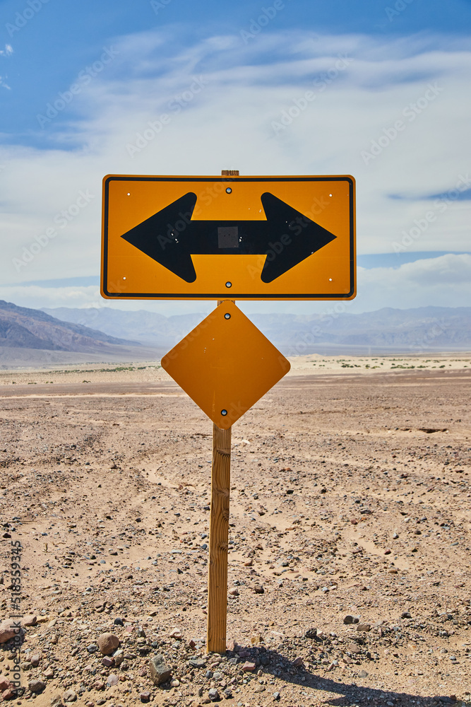 Yellow road sign T intersection left or right in sandy desert