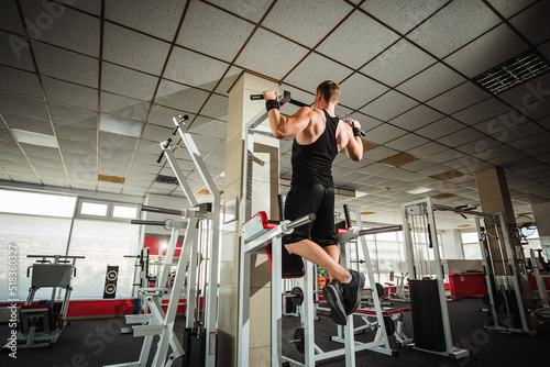 Muscular athlete man in the gym doing elevations. Bodybuilder training in the gym © Shkriabii