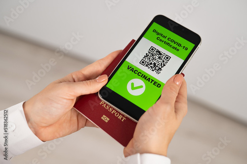 Woman holding passport and phone with qr code about vaccination.