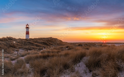 Sonnenuntergang auf Sylt mit dem Leuchtturm List-Ost, romantischem Strand im Vordergrund und einem dramatischen Himmel im Hintergrund