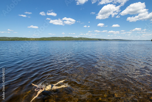 Woman swimming in a clear lake on a summer day