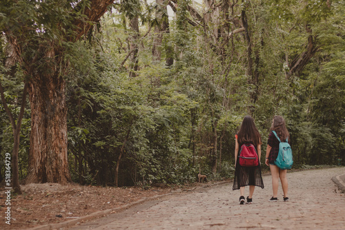two teenager girl friends walking in nature with backpacks