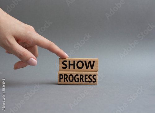 Progress symbol. Wooden blocks with words Show progress. Beautiful grey background. Businessman hand. Business and 'Show progress' concept. Copy space.