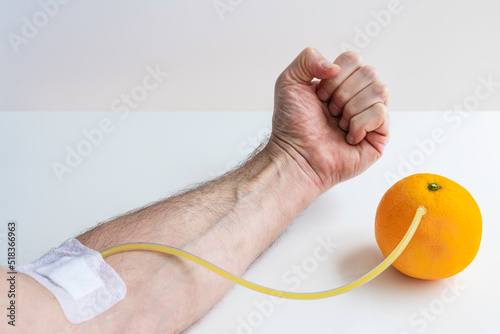 Transfusion of vitamin C from an orange to an arm. Concept on the benefits of vitamin C fruit intake.