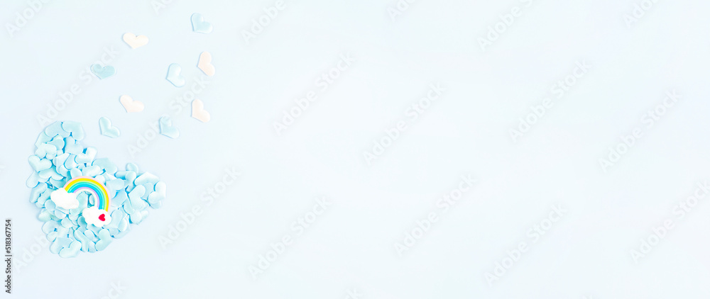 Blurred abstract Blue banner heart made of small hearts with a rainbow in clouds symbol. Flat lay, top view, copy space. Valentine's Day greeting card. Blurred abstract Blue banner heart made of small hearts with a rainbow in clouds symbol. Flat lay, top view, copy space. Valentine's Day greeting card.