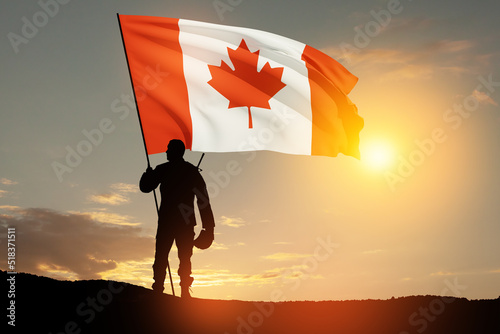 Canada army soldier with Canada flag on a background of sunset or sunrise. Greeting card for Poppy Day, Remembrance Day. Canada celebration. Concept - patriotism, honor. photo