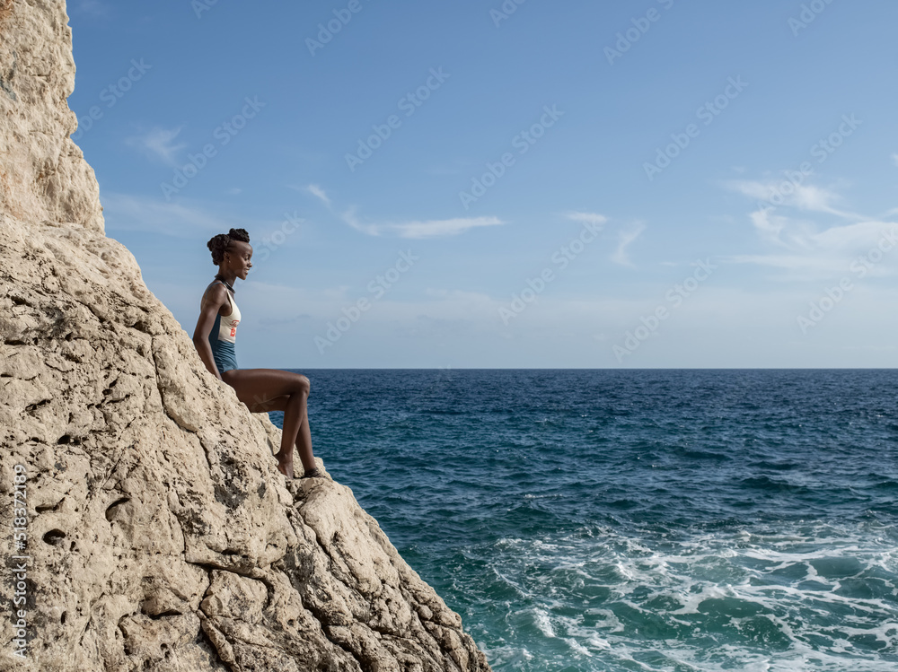 Happy black female resting near waving sea Happy black female resting near waving sea