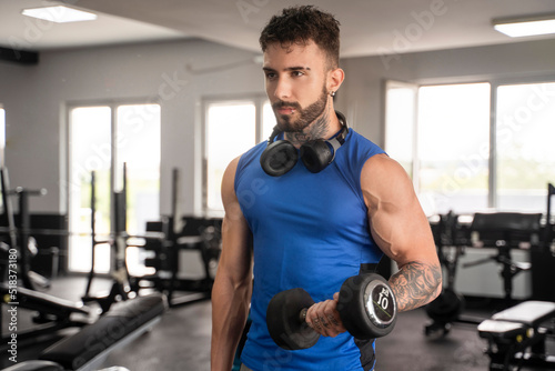 Handsome male with tattoos in his 20s training in the gym