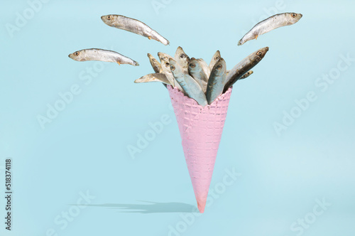 Pinck Ice cream cone with sardinas against pastel blue background. Minimal summer creative concept. Unusual ice cream. photo