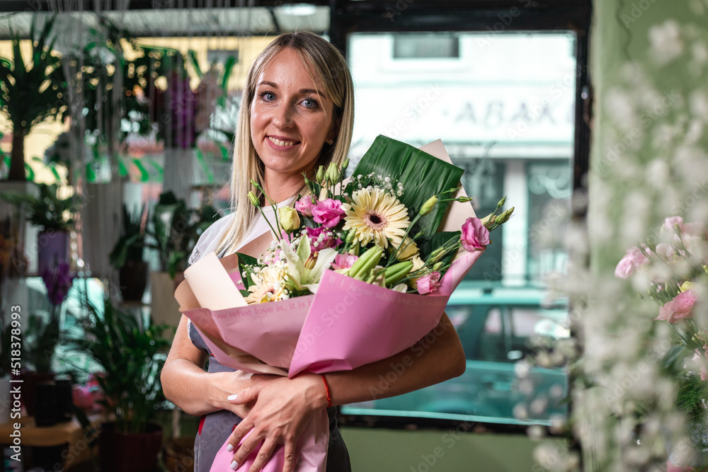 Smiling woman florist small business flower shop owner, at counter, self employed concept.