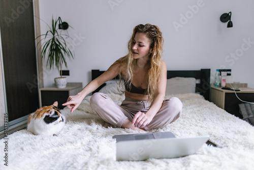 Woman in home clothes teasing cat on plaid  photo