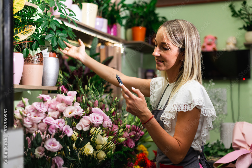 Close up of a young girl florist using a tablet while working in a flower shop..