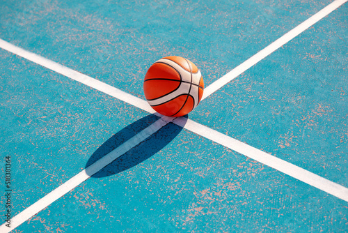 Orange basketball on the markup blue court outside. Team sport concept © Tetiana