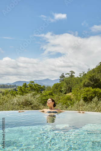 Woman soaking in hot tub pool on vacation at luxury resort and spa
