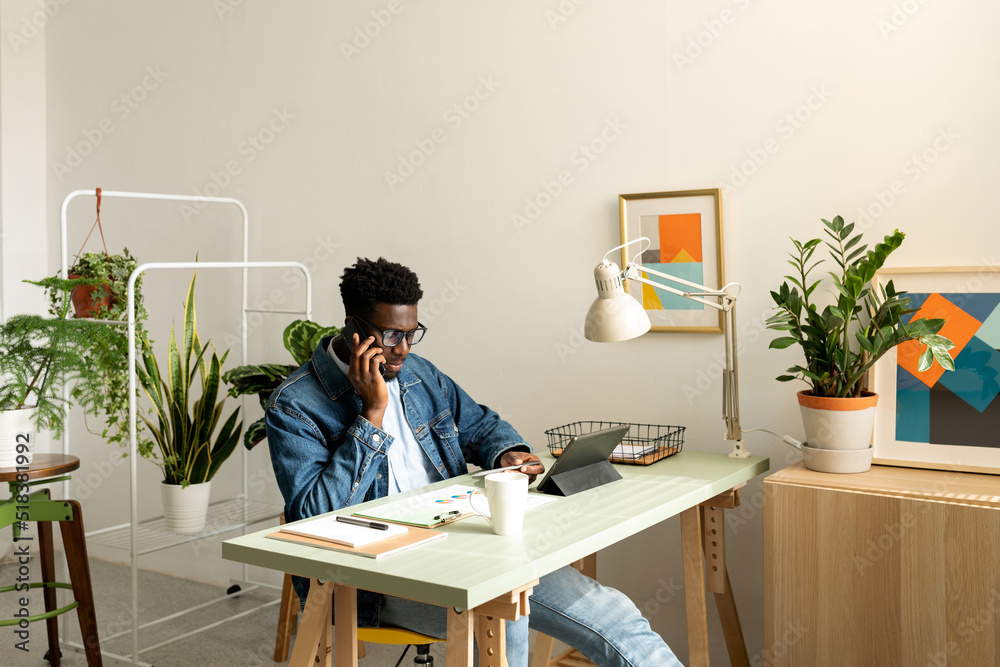 Black man calling by phone at modern office