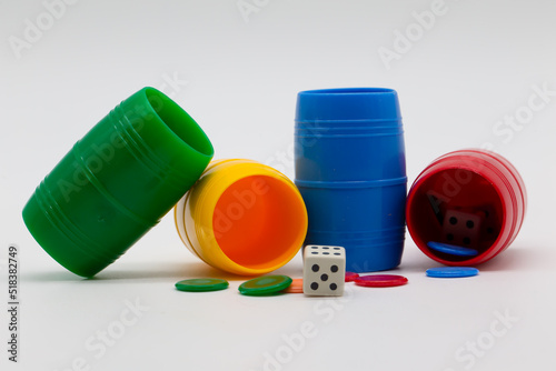 Parcheesi game. Chips, dice and colored cups on a white background. Table games. Family games. photo