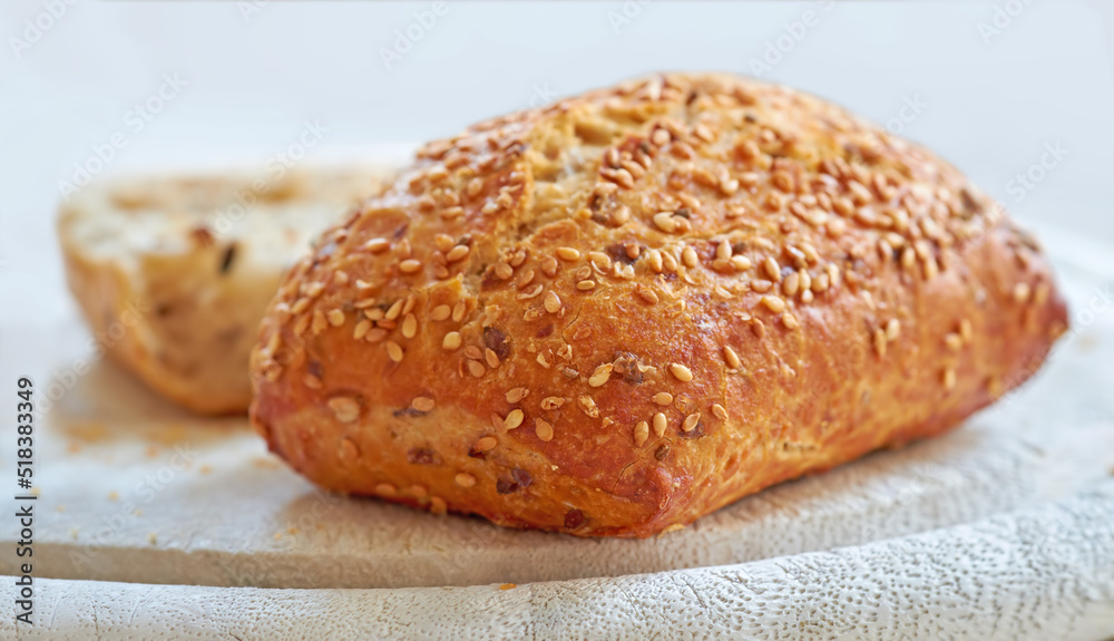 Food stuff. A fresh home baked loaf of wholegrain or wholewheat, sesame seed bread on a board, ready to be cut. For a healthy diet and lifestyle eat food thats high in fibre. Food stuff. A fresh home baked loaf of wholegrain or wholewheat, sesame seed bread on a board, ready to be cut. For a healthy diet and lifestyle eat food thats high in fibre.