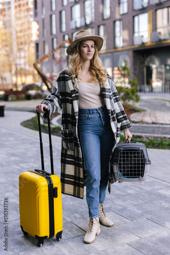 Female tourist standing with yellow valise on empty street 