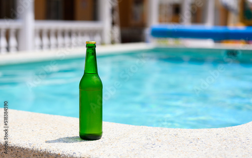 A bottle of cold beer by the pool in a hotel on a hot day. copyspace.