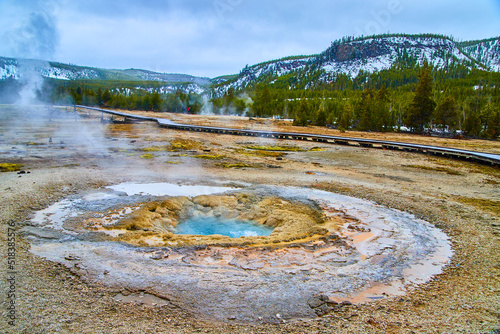 Yellowstone geyser with stunning layers and sulfur steam in winter