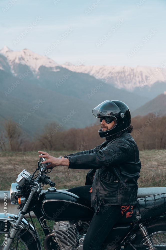 Man sitting on motorcycle near mountains