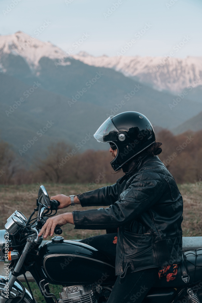 Man sitting on motorcycle near mountains Man sitting on motorcycle near mountains