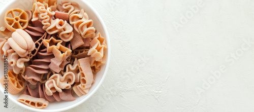 Pink Italian pasta in white bowl on a light background. Concept alternative pasta. Horisontal orientation. copy space. Top view. Banner