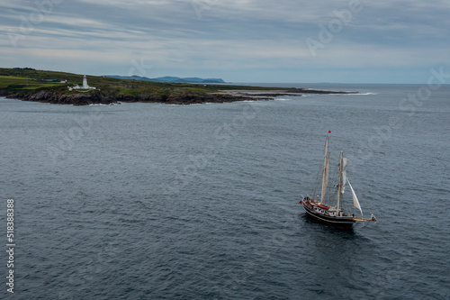 view of the Fanad Head Lighthouse on the northern coast of Ireland with an old two-masted sailboat sailing away photo