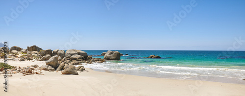Calm beach with white sand on a rocky natural seaside environment in a popular getaway location for a holiday in Cape town. Landscape of the ocean on a sunny day with blue sky and copy space
