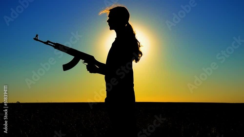 Ukraine War. A young man with a Kalashnikov assault rifle trains in the field. Silhouette of a man with a Kalashnikov assault rifle. The concept of war, terrorism, aggression against Ukraine. photo