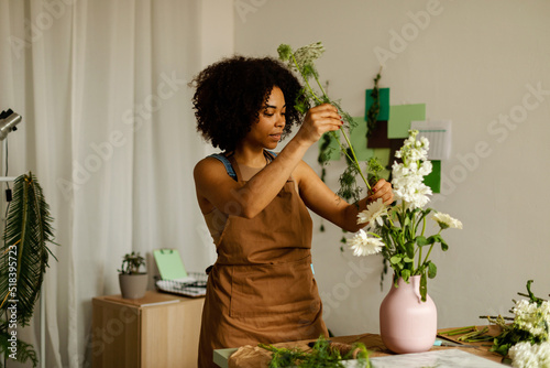 Florist owner putting natural flowers inside ceramic vase photo