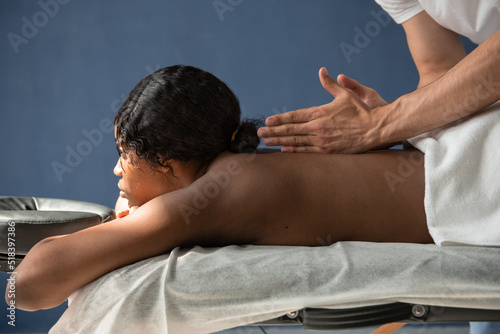Black woman lying on table during back massage