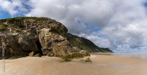 panorama landscape view of Maghera Beach with the entrance to one of the caves in the rocks