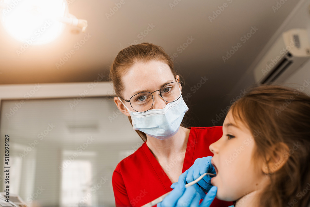 Consultation with pediatric dentist at dentistry. Teeth treatment. Children dentist examines girl mouth and teeth and treats toothaches. Happy child patient of dentistry.