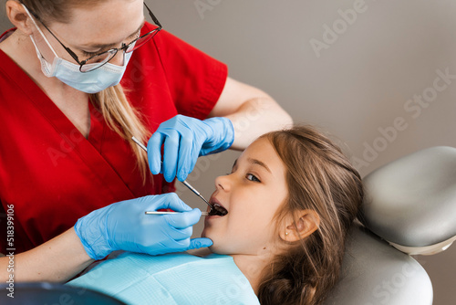 Pediatric dentist and cheerful girl child smiling in dentistry. Child smiles at the consultation with dentist. Creative advertising for dentistry.