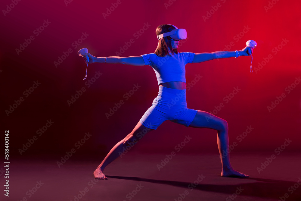 woman practices yoga in VR headset, modern technology glasses  with neon light  on a colored background